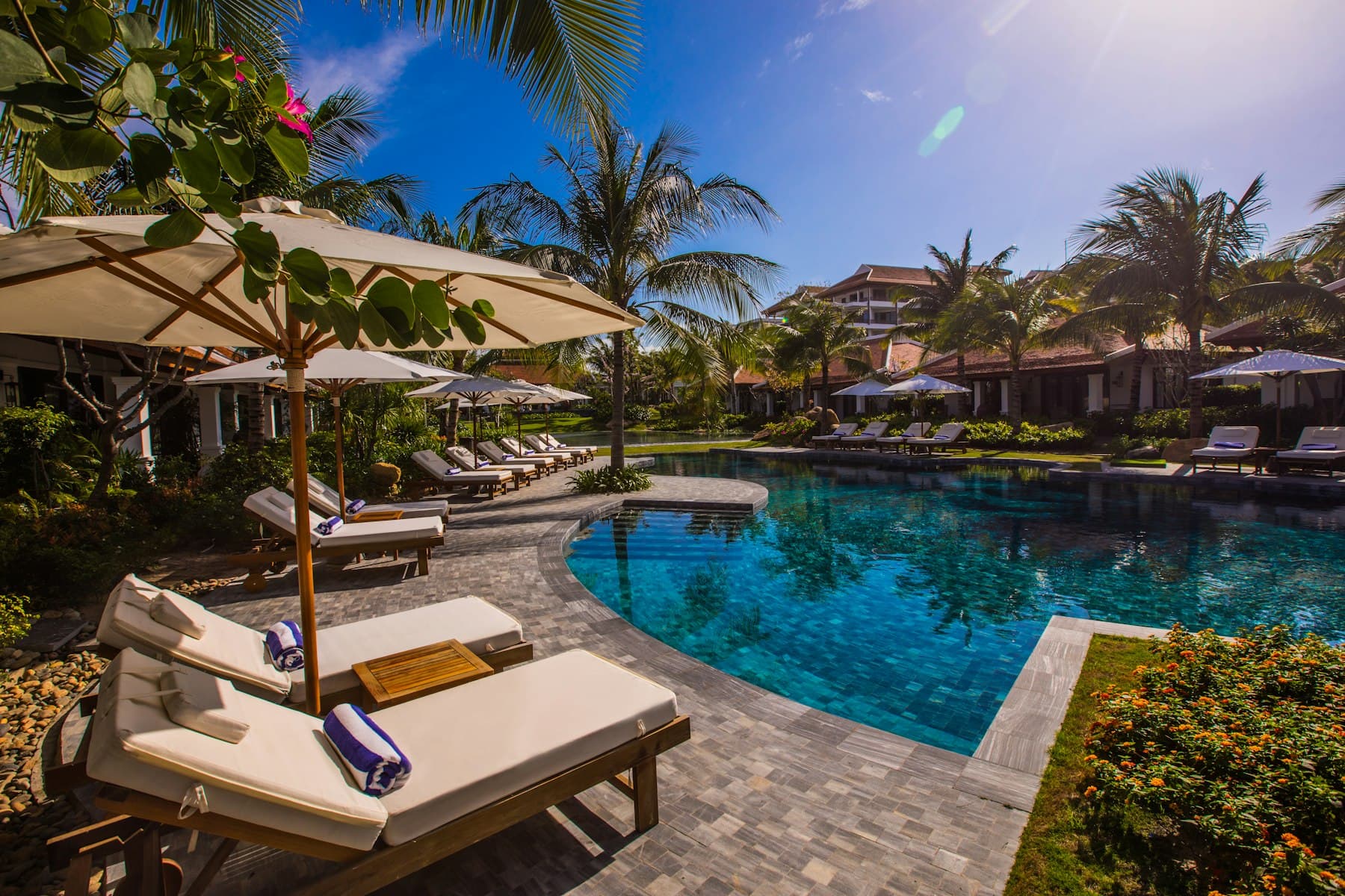 Espreguiçadeiras e chapéus de sol junto a uma piscina